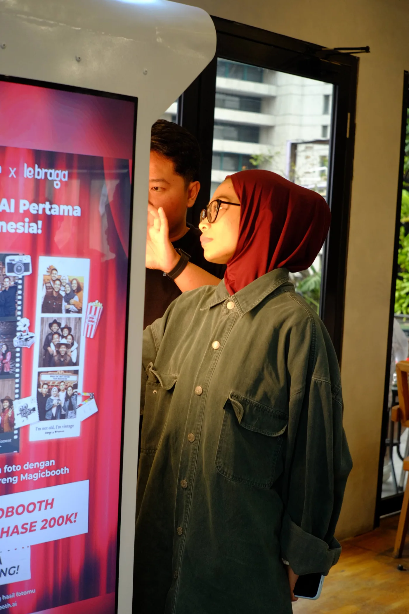 Pengunjung mencoba photobooth AI Magicbooth di venue dengan area duduk dan jalur pengunjung
